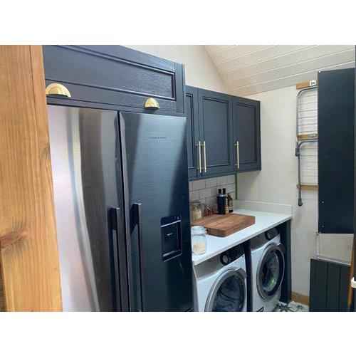 Black American style fridge freezer with navy cabinets above and washing machine to side 500x500