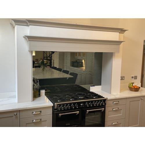 Black range cooker with mirrored splash back reflecting kitchen seating area 500x500