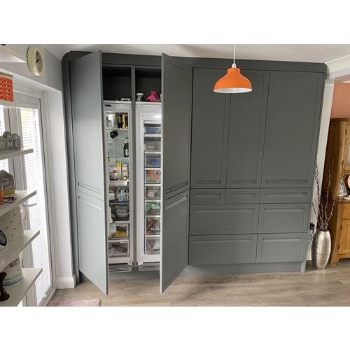 Custom built full height grey kitchen cabinets with open doors showing built in fridge and freezer 500x500