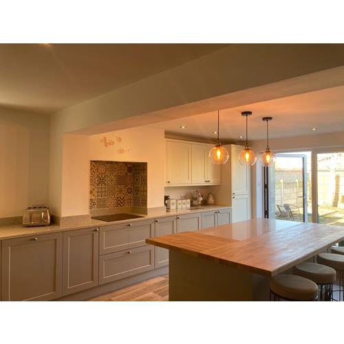 Fitted kitchen with large kitchen island light grey cabinets and patio doors overlooking garden 500x500