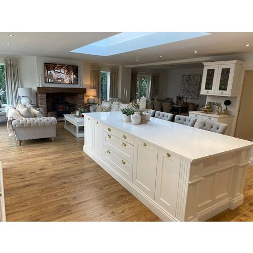 Fitted kitchen with large kitchen island white cabinets quartz worktops and sofa area in front of fireplace 500x500
