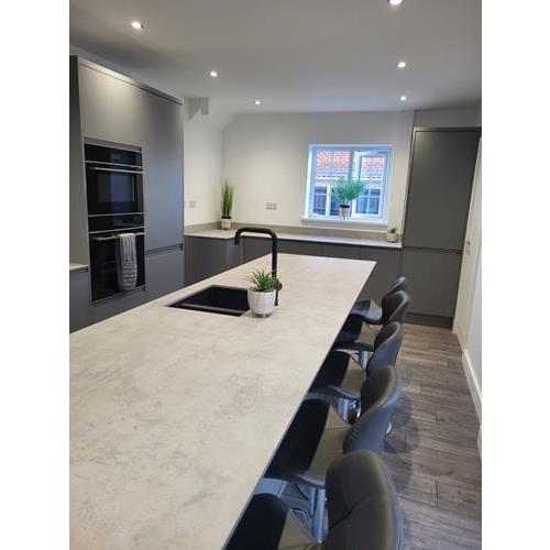 Large kitchen island with marbled worktop barstool seating and grey fitted cabinets 500x500