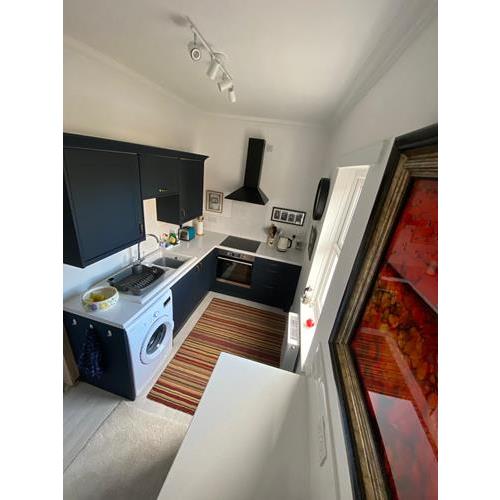 Overhead view of a modern fitted kitchen with navy cabinets white worktops and colourful striped rug 500x500
