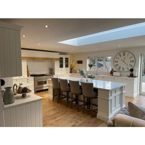 Traditional style fitted kitchen with white cabinets and large island with seating 500x500