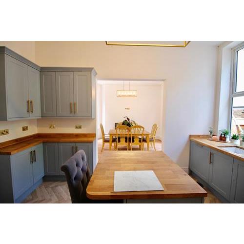 View of kitchen with grey fitted cabinets through to dining room with pine table and chairs 500x500