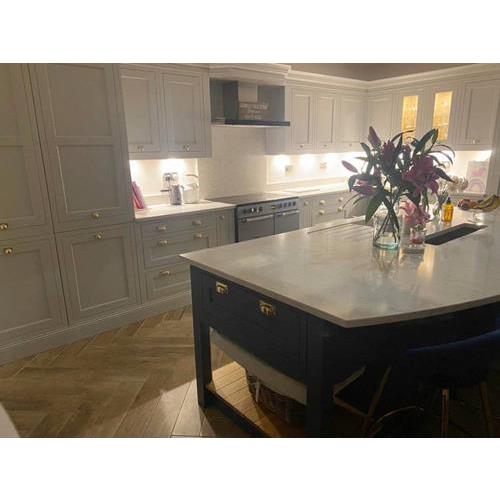 White fitted kitchen with under cabinet lighting and large island with vase of lilies 500x500